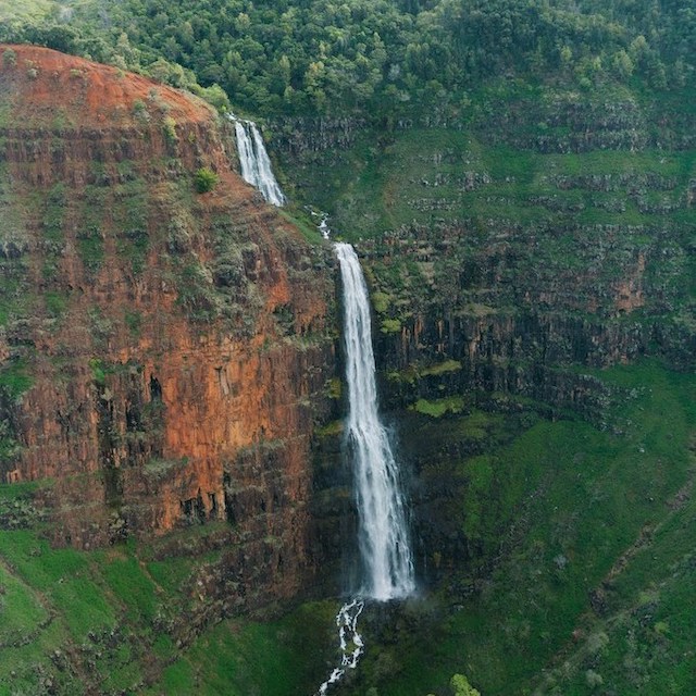 Close up of Waipoo Falls, Kauai waterfall in Waimea Canyon, surrounded by red rocks and greenery
