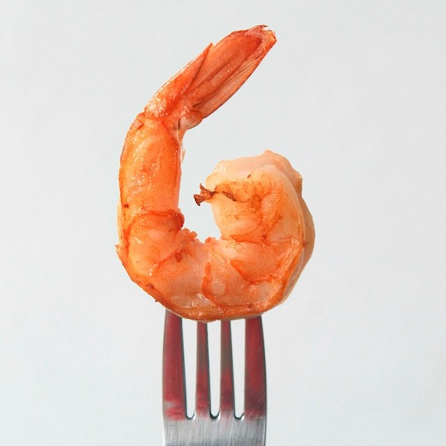 close up of a fork skewering a full cooked shrimp