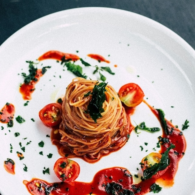 A fancy angel hair pasta dish, swirled into a tall tower and drizzled with a tomato and basil-based sauce, along with a few halved cherry tomatoes. If you're in the mood for Italian like this, Osteria Mozza Lanai is the best restaurant for Italian on Lanai.